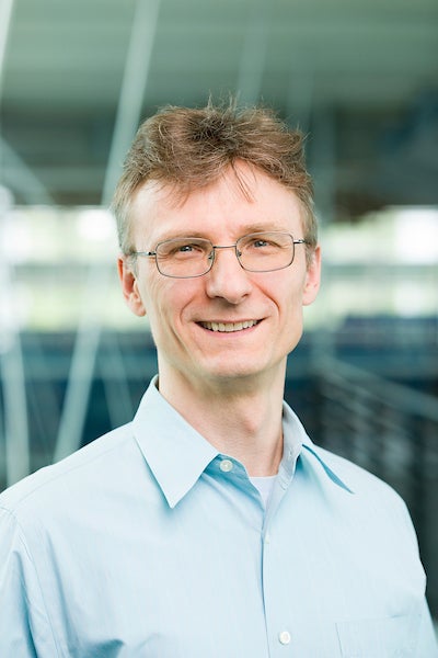 blonde man in glasses and light blue shirt smiling at camera