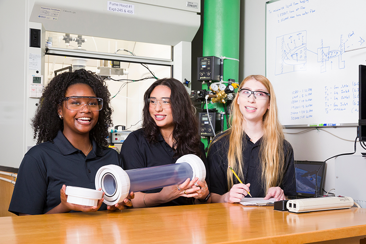 three women in engineering lab holding a tube