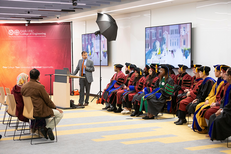 man in suit talking to phd graduates in regalia