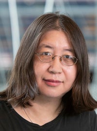 woman with brown hair and glasses wearing black shirt looking at camera