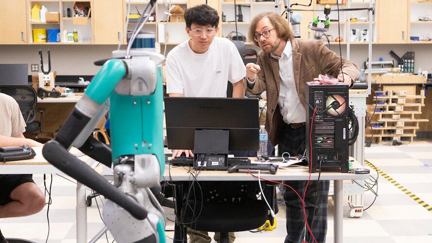 Graduate Research Assistant Tianze Wang (left) with Dr. Christian Hubicki in Dr. Hubicki's lab with "Digit" the robot in the Center for Intelligent, Systems, Control, and Robotics (CISCOR) in the Aero-propulsion, Mechatronics, and Energy Center (AME) of FAMU-FSU College of Engineering in Tallahassee, Florida on June 27, 2024.