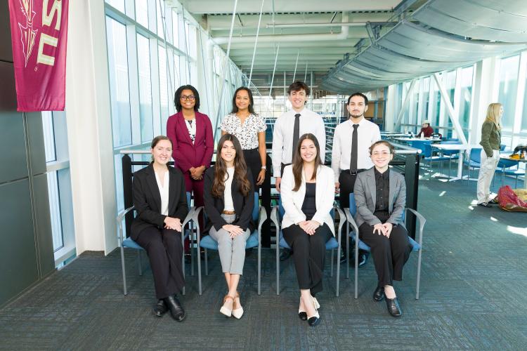 The eight members of engineering senior design team 109 stand together on the third floor breezeway at the FAMU-FSU College of Engineering.