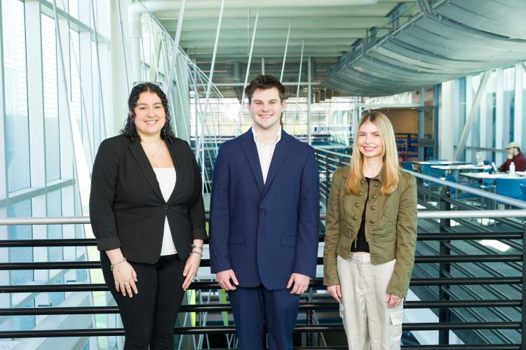 The three members of engineering senior design team 112 stand together on the third floor breezeway at the FAMU-FSU College of Engineering.