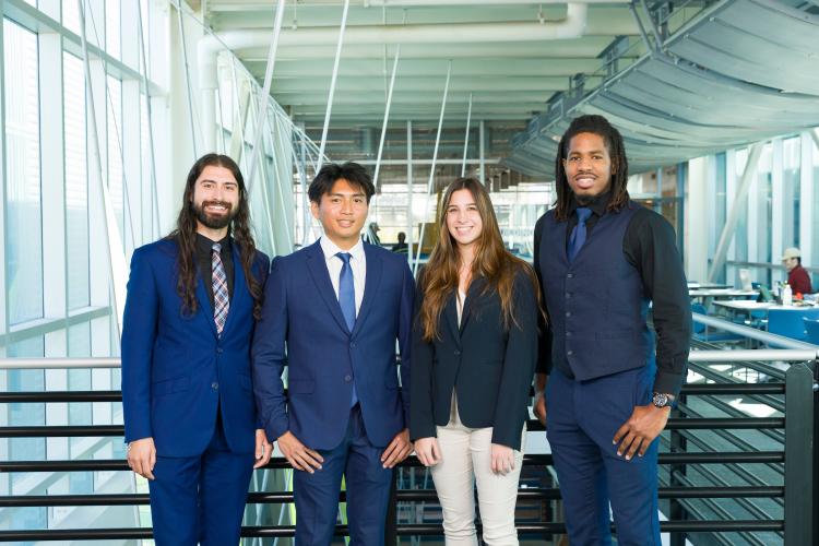 The four members of engineering senior design team 114 stand together on the third floor breezeway at the FAMU-FSU College of Engineering.