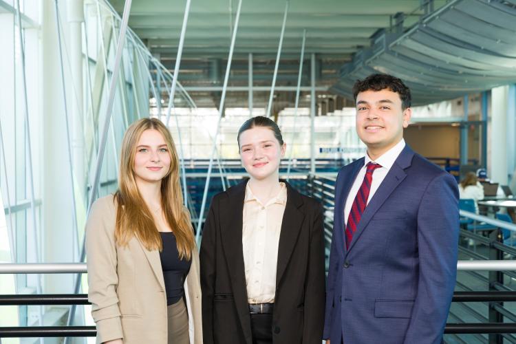 The three members of engineering senior design team 115 stand together on the third floor breezeway at the FAMU-FSU College of Engineering.