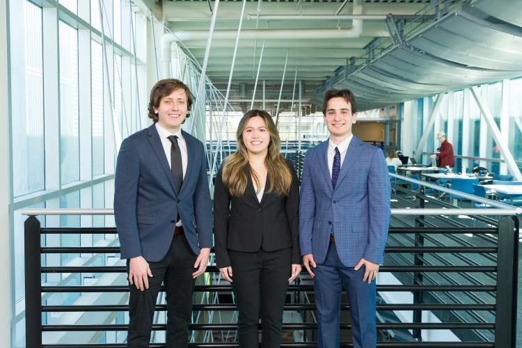 The three members of engineering senior design team 116 stand together on the third floor breezeway at the FAMU-FSU College of Engineering.