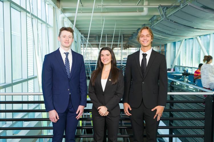 The three members of engineering senior design team 204 stand together on the third floor breezeway at the FAMU-FSU College of Engineering.