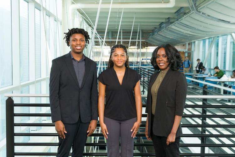 The three members of engineering senior design team 220 stand together on the third floor breezeway at the FAMU-FSU College of Engineering.