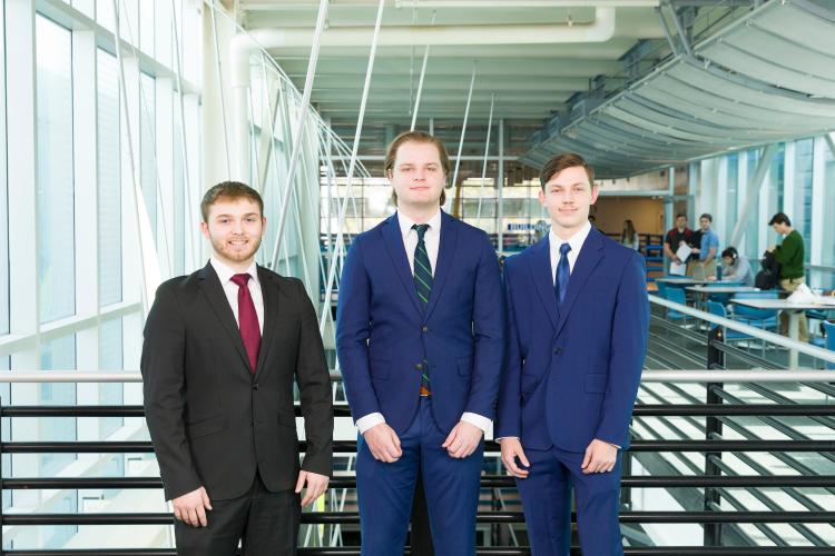 The three members of engineering senior design team 221 stand together on the third floor breezeway at the FAMU-FSU College of Engineering.