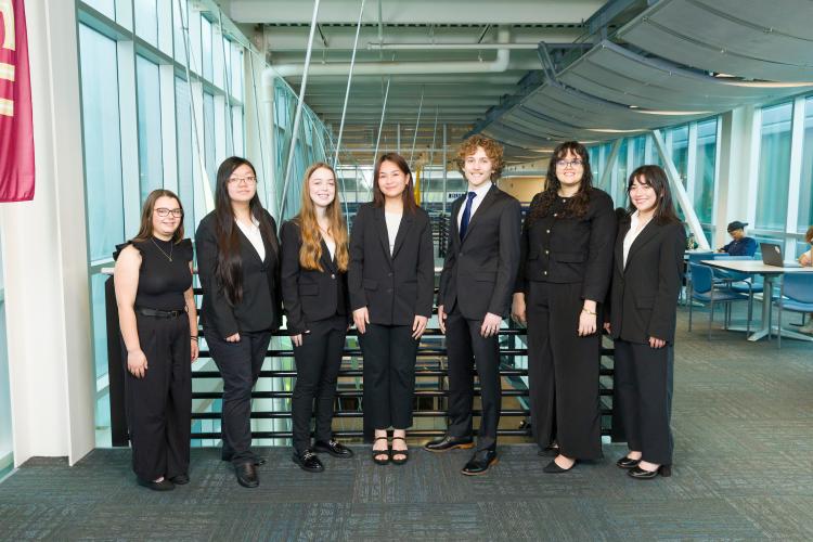 The seven members of engineering senior design team 108 stand together on the third floor breezeway at the FAMU-FSU College of Engineering.