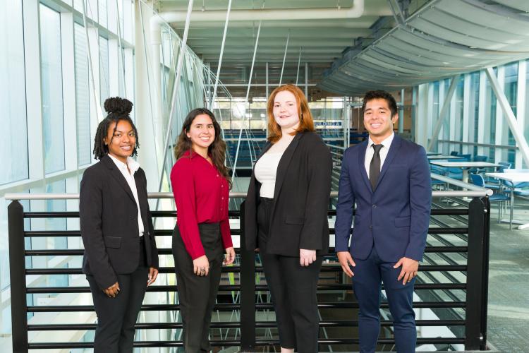 Four members of engineering senior design team 408 stand together on the third floor breezeway at the FAMU-FSU College of Engineering. The team contains six members, two of who are not pictured.