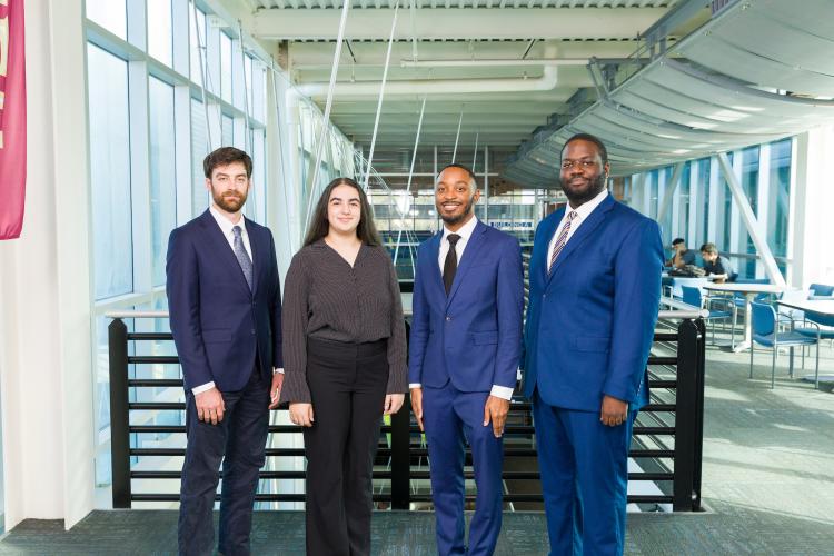 Four members of engineering senior design team 514 stand together on the third floor breezeway at the FAMU-FSU College of Engineering. The team contains five members, one of who is not pictured.