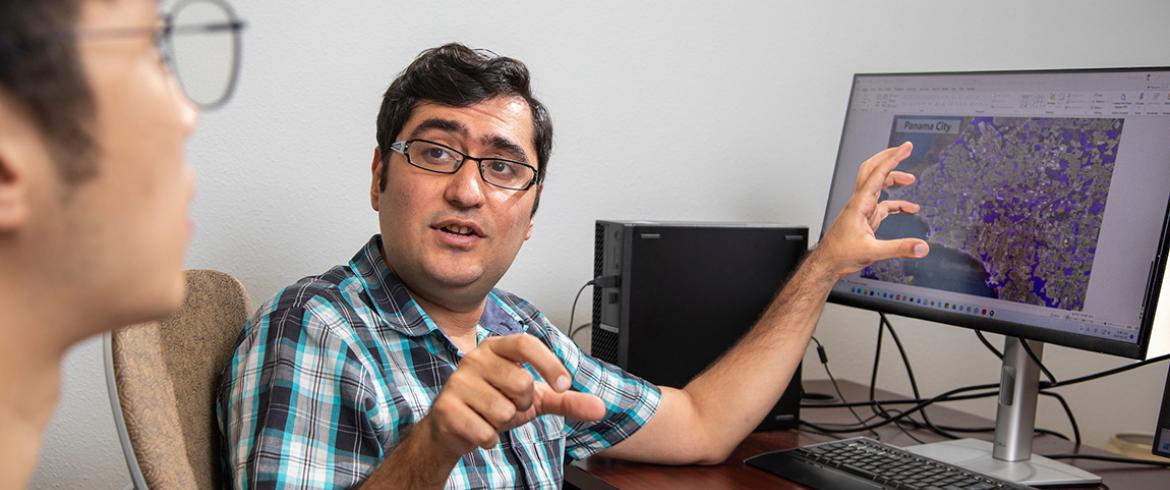 photo of ebrahim ahmadisharaf at a computer explaining flood modeling engineering to a student at the famu-fsu college of engineering