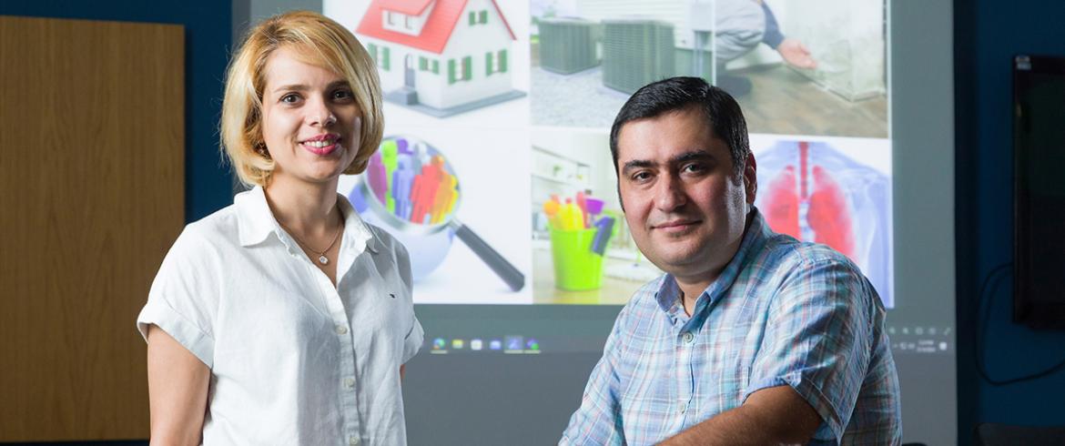 photo of two engineering researchers in front of several images of mold locations in buildings