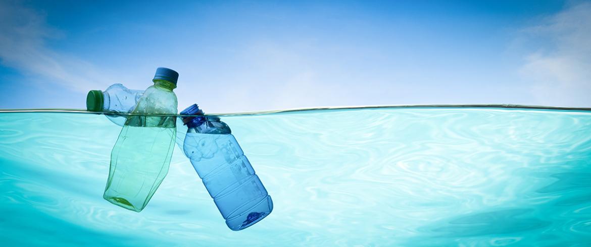 photo of two plastic bottles floating in water with blue sky