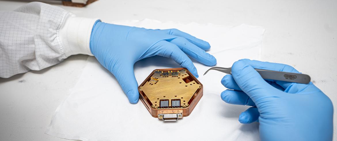 photo of two hands with tweezers over octagon-shaped disc