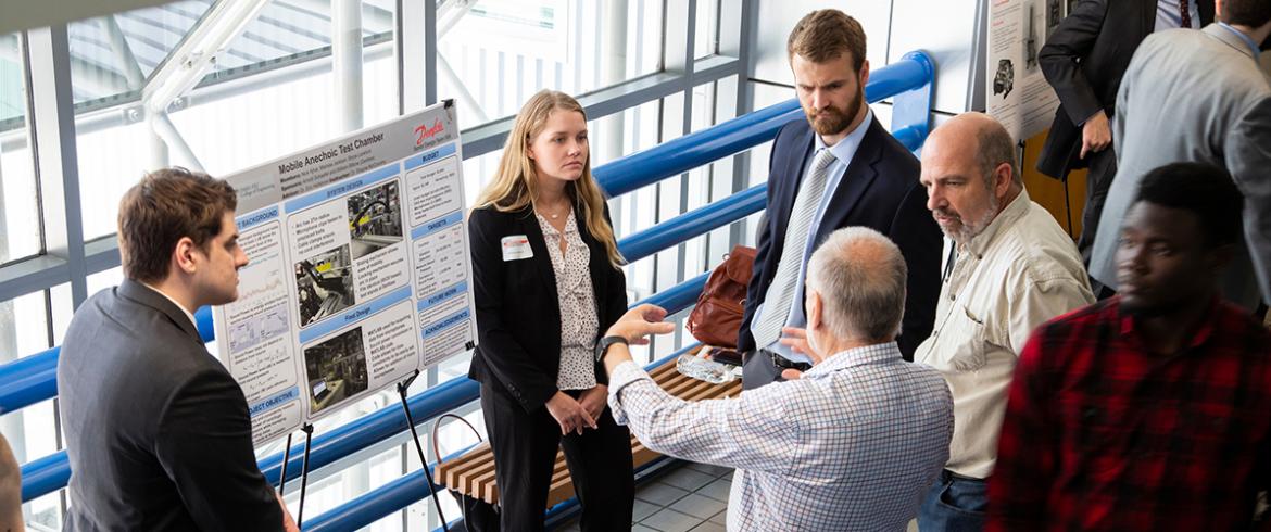 photo of engineering students and judges discussing research poster