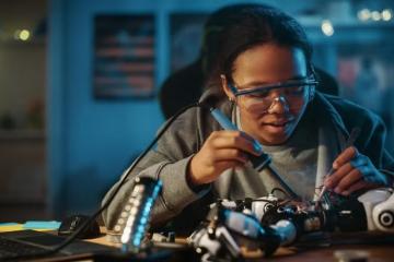 Black female engineering student soldering a unit