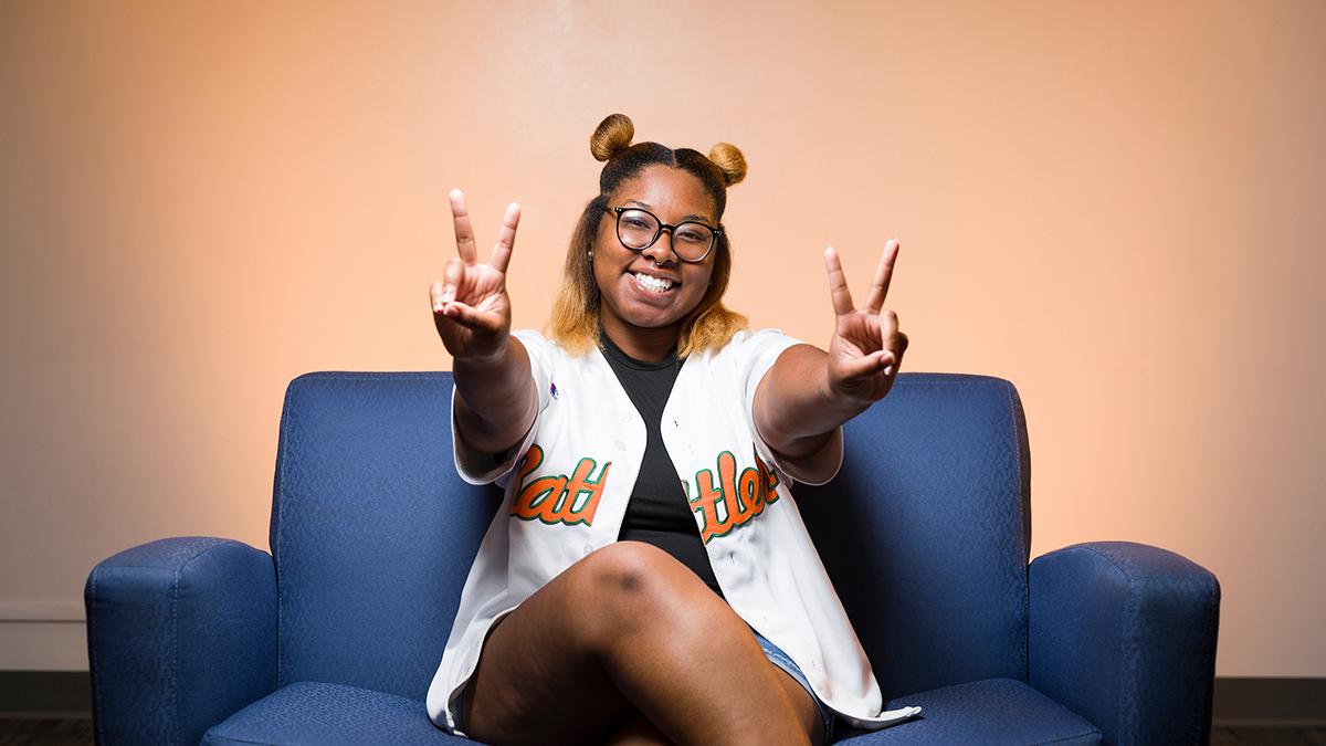 photo of nia britton on blue couch holding up two peace signs smiling