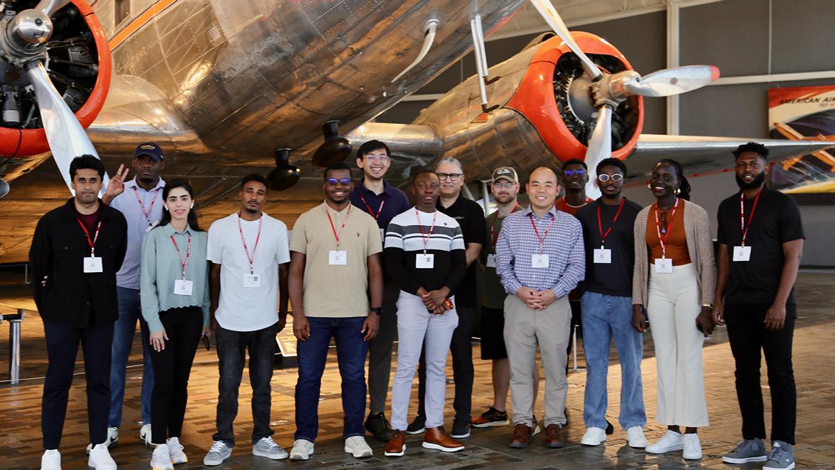 photo of group of students in front of antique silver airplanes