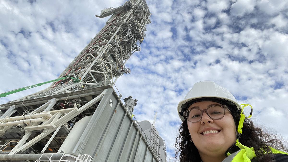 gabrielle mayans in front of large metal crane