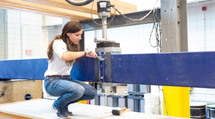 Female structures students secures a device to a beam