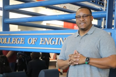photo of man in glasses and gray polo shirt with hands clasped at chest in the college of engineering
