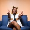 photo of nia britton on blue couch holding up two peace signs smiling